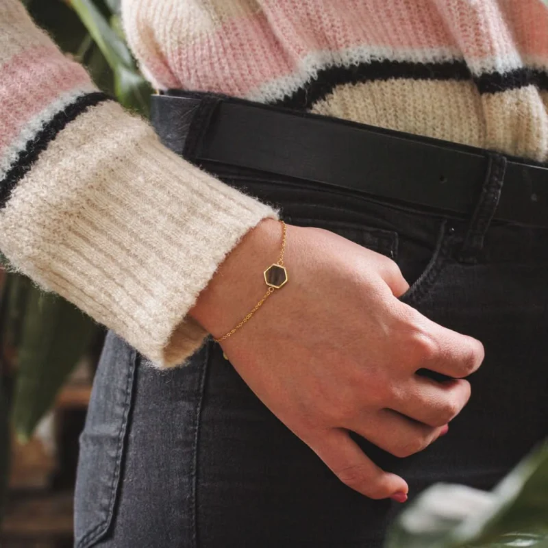 Goldfarbenes Armband mit eckigem Holzanhänger auf Handgelenk