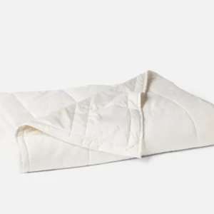 Coyuchi Washable Wool Filled Comforter in ivory, folded to show diamond quilt stitching.