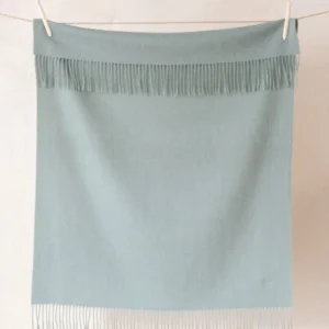 TBCo Lambswool Baby Blanket in Sage Melange hanging on clothesline, featuring soft fringe detail and gentle sage green colour