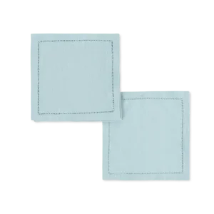The Valentina Hemstitch Cocktail Napkin Set by Matouk features two light blue linen napkins with hemstitch borders—an elegant touch for any luxurious tabletop.