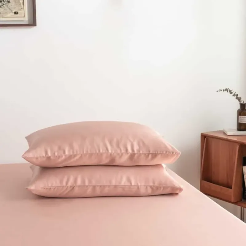 Cuddle Pink bamboo pillowcases styled on a bench in a bedroom setting