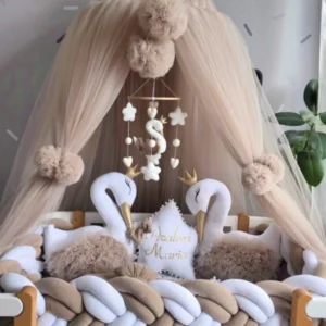 Nursery crib with canopy, swan decorations, and a mobile above.
